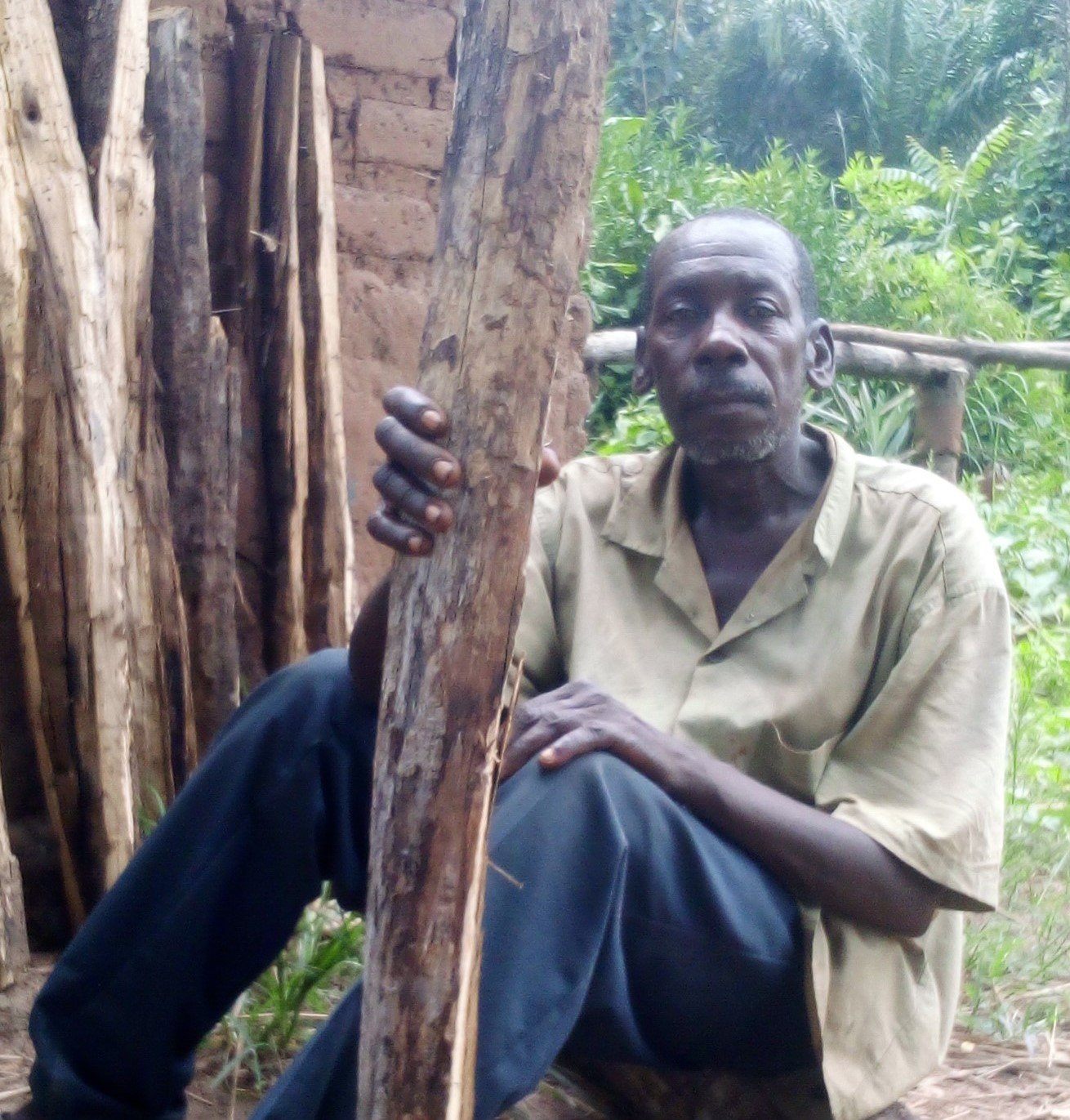 Angelo Patrick Gbudu beside firewood in Nzara County